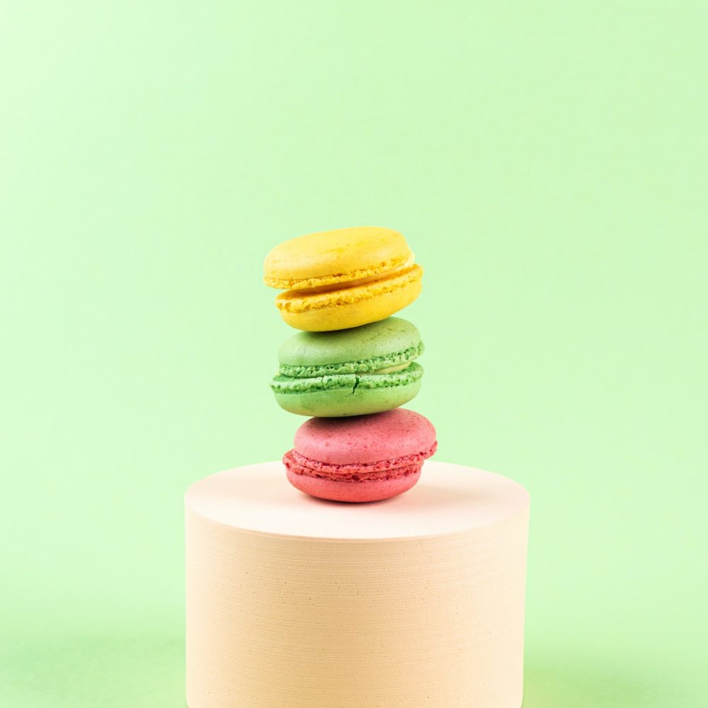 geometric-pastel-green-background-with-colorful-macaroon-sweet-candies-on-circle-podium